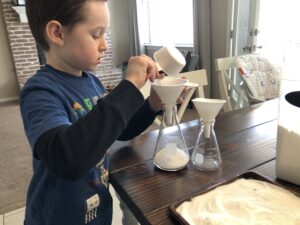 Kid mixing baking soda and vinegar in a glass bottle