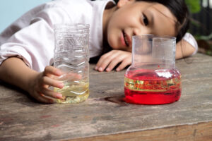School kid making oil and water separator experiment at home