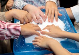Children touch and play with artificial snow during the holiday