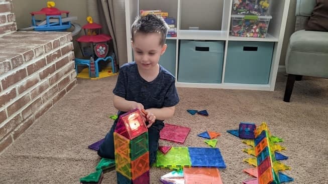 A toddler playing with magnetic tiles