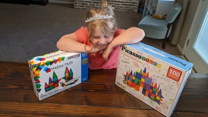 Girl with two boxes of magnet tiles