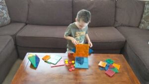 A toddler playing connect four with magnetic tiles