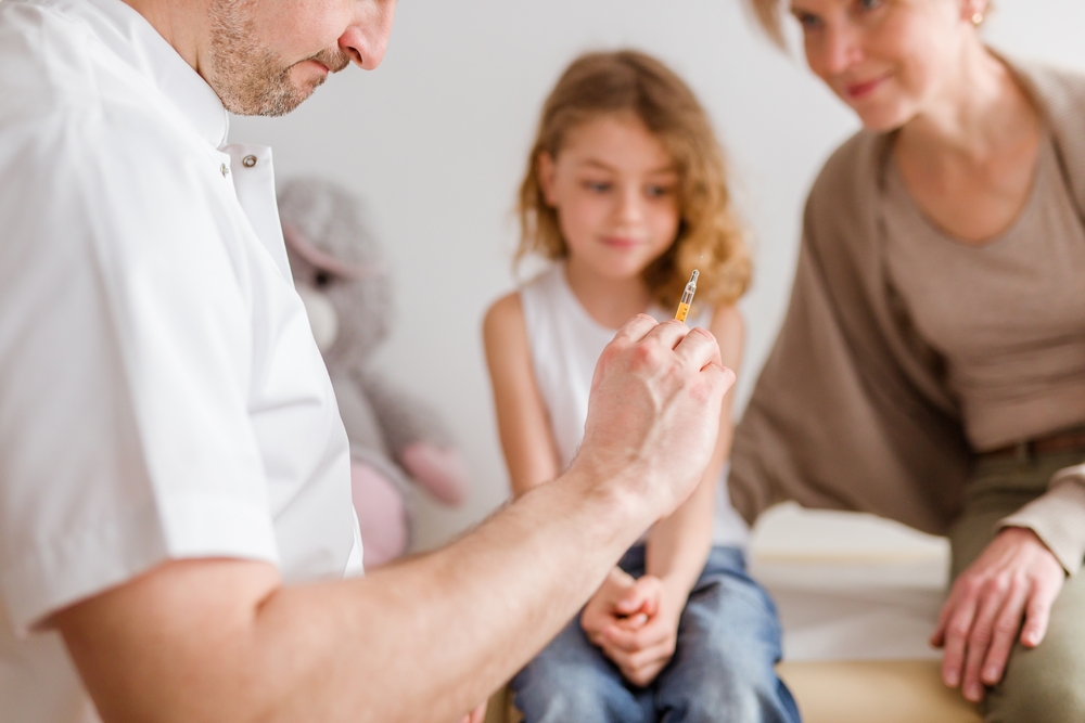 Pediatrician with the syringe preparing the vaccine for a girl