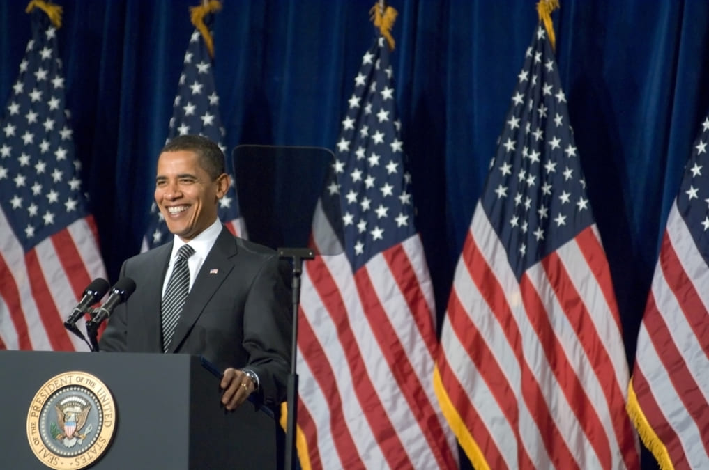 photo of barack obama in a podium with US flag behind him.