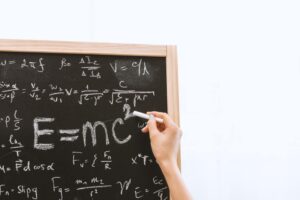 hand writing formula and e=mc2 at a chalkboard.