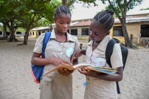 girl students wearing school uniform and reading a notebook.