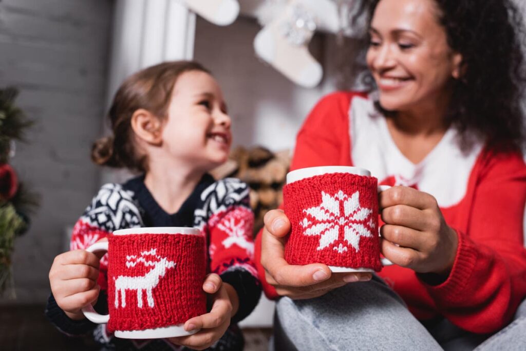 Mother and daughter holding cups during winter time.